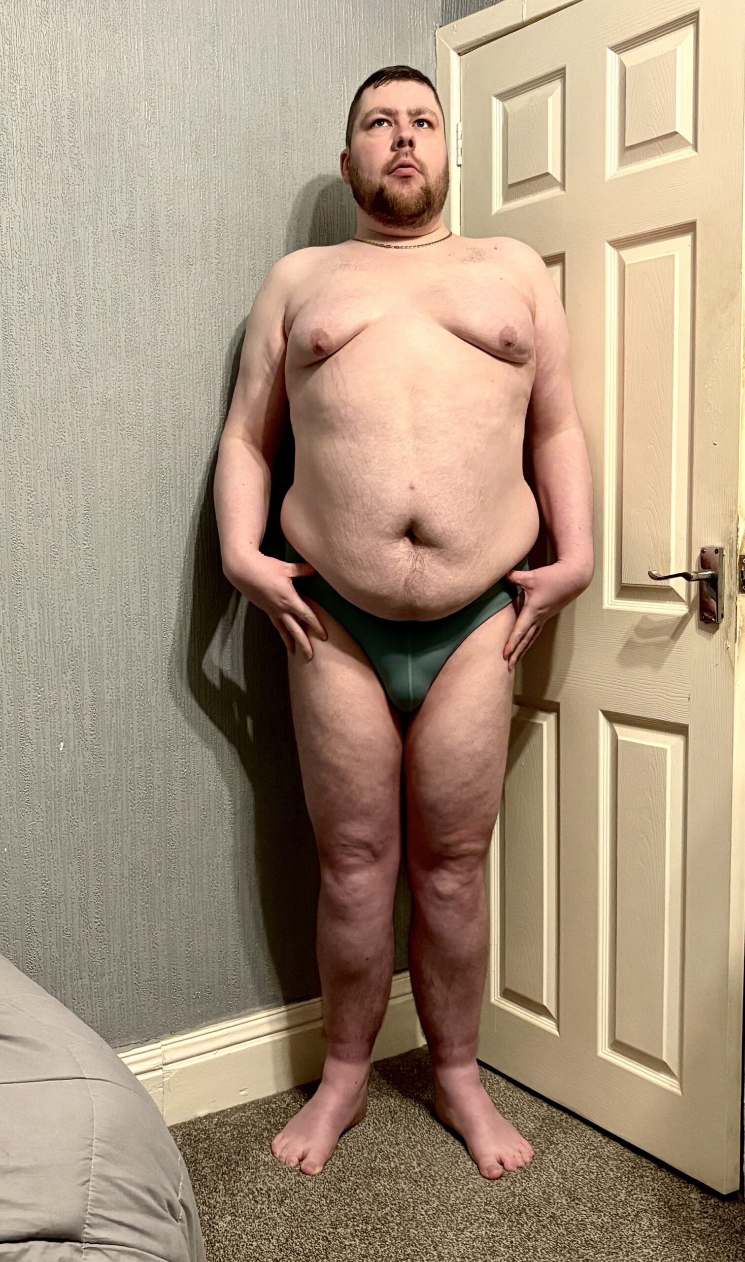 Gliding Past Uranus On My Trip Through The Universe | Box Menswear Celestial Green Glide Briefs A tall bearded man with his hands on his hips wearing a pair of dark green briefs with a dark green waistband that has Box Menswear written in bold black writing on it stood against a white wooden door.