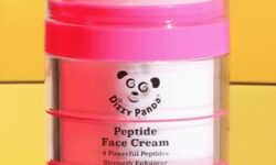 A short and wide gradient bright pink and white plastic tub with a bright pink plastic lid and a bright white label that has Dizzy Panda Peptide Face Cream written in bold black writing and a picture of a Panda’s Face on it, on a white background.