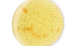 A medium circular puddle of some glossy creamy ivory shower gel that has some pieces of bright gold lustre running through it, on a white background.