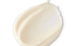 A medium circular puddle of some thick, creamy pale yellow Body Butter, on a white background.