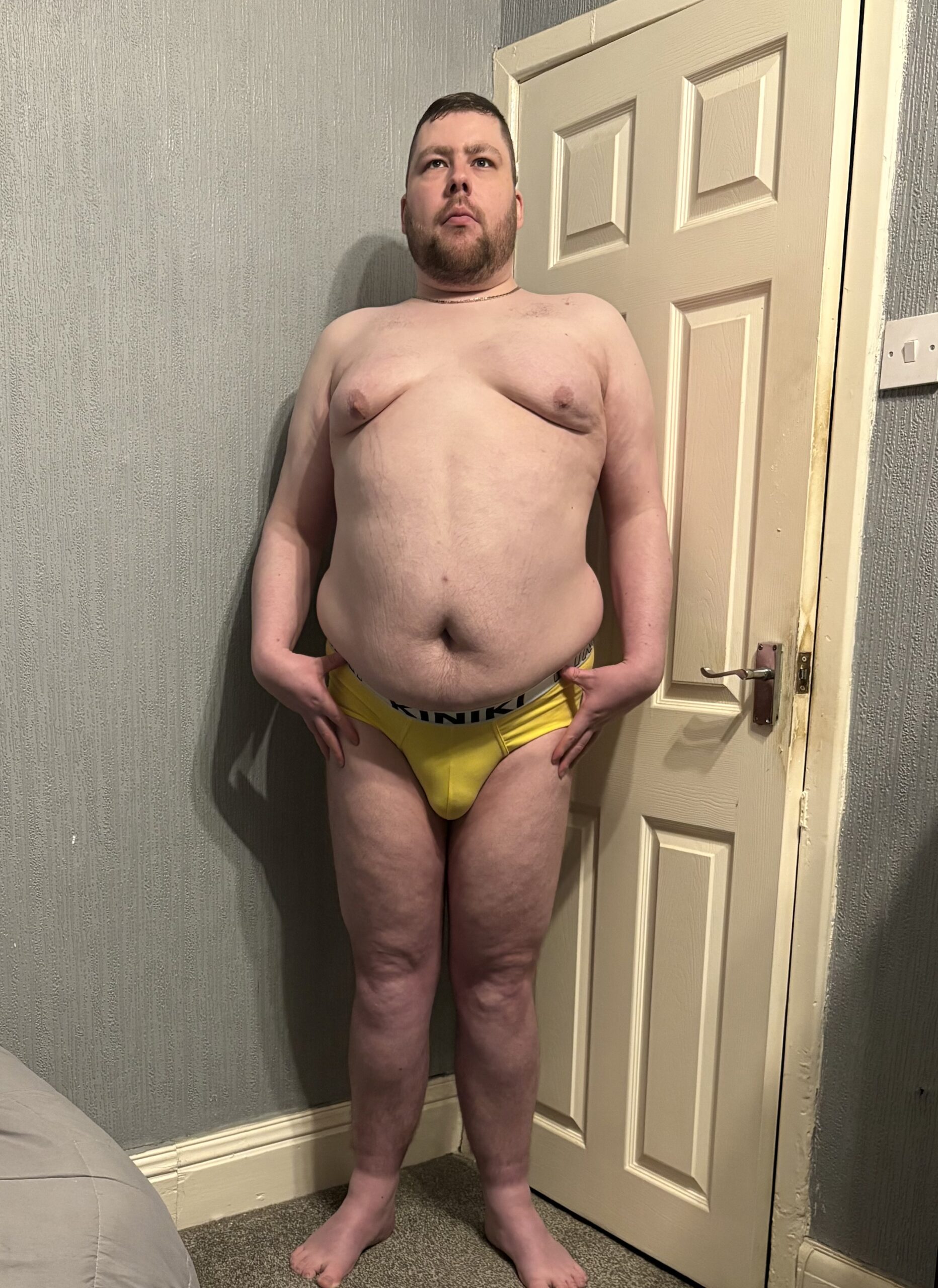 Pounding The Streets Of Oxford In Amazing Pants Yet Again | Kiniki Yellow Oxford Brief A tall bearded man with his hands on his hips wearing a pair of bright yellow briefs with a black waistband that has Kiniki written in bright white writing on it stood against a white wooden door.