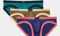 A pair of folded up bright turquoise briefs that has some Black trim all over them next to a pair of folded up dark olive green briefs that has some beige trim all over them, and a pair of folded up dark navy blue briefs that has some salmon pink trim all over them that all have a small rectangular black label that has Awry written in bright writing on them, on a white background.