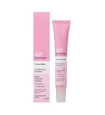 A long and thin conical gradient bright pink and white plastic Tube with a bright white plastic lid that has Boots DermaCare Ceramides Conditioning Eye Balm written in bold black writing on it next to a tall rectangular gradient bright pink and white cardboard box that has Boots DermaCare Ceramides Conditioning Eye Balm written in bold black writing on it, on a white background.