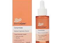 A short cylindrical clear glass bottle full of some translucent bright orange liquid with a bright white rubber pipette lid and a gradient bright orange and white label that has Boots DermaCare Ceramides Intense Hydration Serum written in bold black writing on it next to a short cylindrical gradient bright orange and white cardboard box that has Boots DermaCare Ceramides Intense Hydration Serum written in bold black writing on it, on a white background.
