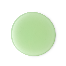 A medium circular puddle of some thick glossy pale lime green shower gel, on a pale grey background.