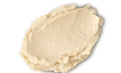 A medium circular puddle of some light beige Shampoo, on a white background.
