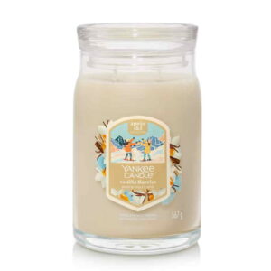 A tall cylindrical glass Jar full of some creamy white Wax with a Label that has Yankee Candle written in bright white writing, Vanilla Flurries written in bright white writing, and a picture of two people holding some bright white snowballs surrounded by a snowy landscape on it, on a white background.
