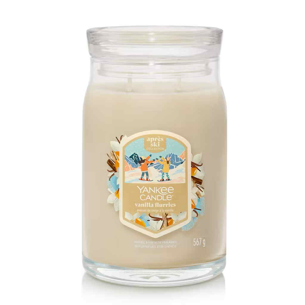 What I Thought of the Yankee Candle Advent House 2014 A tall cylindrical glass Jar full of some creamy white Wax with a Label that has Yankee Candle written in bright white writing, Vanilla Flurries written in bright white writing, and a picture of two people holding some bright white snowballs surrounded by a snowy landscape on it, on a white background.