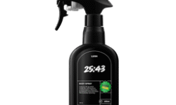 A tall black plastic kitchen spray bottle with a black plastic spray trigger nozzle that has Lush 25:43 Body Spray written in bright white writing and a circular bright green sticker that has Lush Club written in bright white writing on it, on a bright white background.