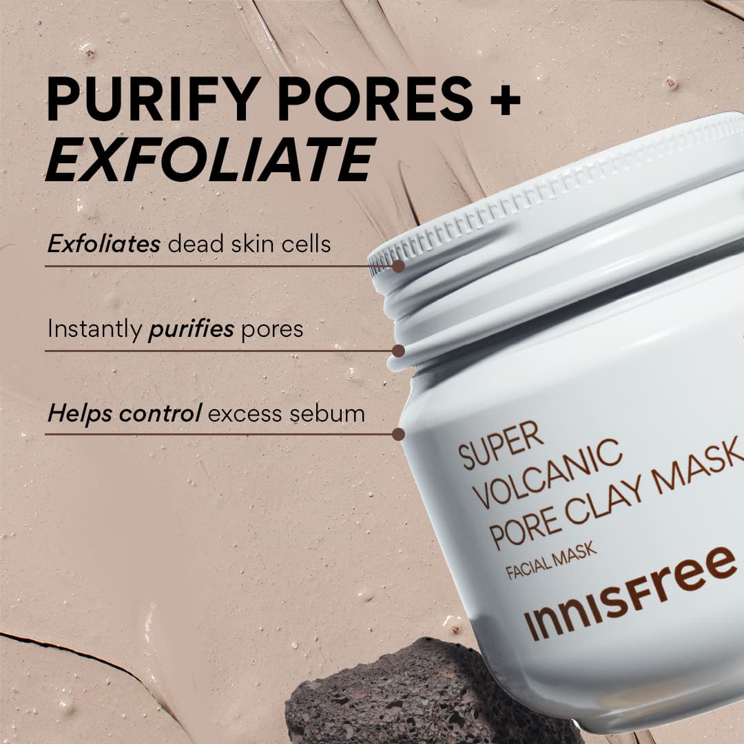 I’m Finally Free Of Clogged Pores! | Innisfree Super Volcanic Clay Pore Mask A short cylindrical bright white Plastic Tub with a bright white Plastic Lid that has INNISFREE Super Volcanic Pore Clay Mask written in dark brown writing on it surrounded by some small smudges of dark grey volcanic clay and a medium piece of dark grey rock, on a light beige background.