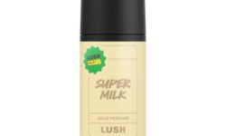 A short cylindrical black cardboard tube with a black cardboard lid and a pale yellow label that has Lush Super Milk Solid Perfume written in bright white writing on it, on a white background.