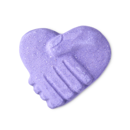 Because The Hand Of Friendship, Speaks Without Words | Lush Hand Of Friendship Bath Bomb A medium bright purple heart shaped bath bomb that has two large hands clasped together in a handshake engraved on it and some bright purple lustre all over it, on a white background.