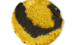A medium circular swatch of some thick, bright mustard yellow cleanser that has a swirl of black charcoal running through it, on a white background.