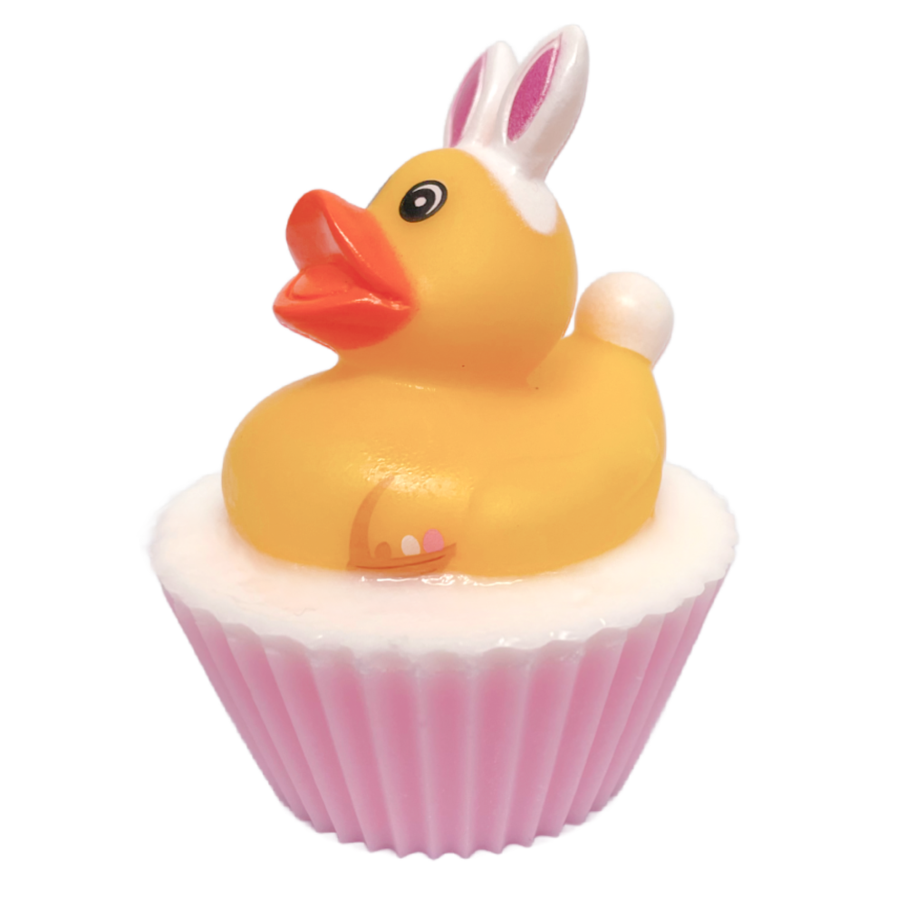 The Ducks In Yorkshire Are Absolutely Quackers For Easter | The Yorkshire Soap Company Easter 2026 Range A large circular bright white cupcake shaped block of soap that has a light pink paper cupcake case around it and a bright yellow Rubber Duck with a bright orange beak, a large black eye, some bright white bunny ears, and a bright white puffy Tail sat on top of it, on a white background.