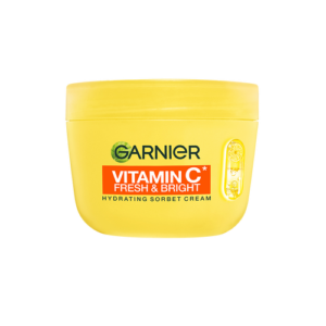 A short cylindrical bright yellow plastic tub with a bright yellow plastic lid and a dark orangey red label that has Garnier written in dark green writing, Vitamin C* Fresh & Bright written in bright white writing, Hydrating Sorbet Cream written in bold black writing, and a picture of some large slices of citrus fruits on it, on a white background.