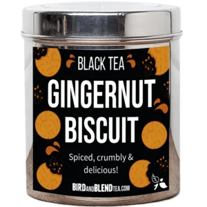 A tall cylindrical bright silver metal tin with a bright silver metal lid and a black label that has Gingernut Biscuit loose Leaf Tea written in bright white writing and some pictures of some golden brown gingernut Biscuits on it, on a white background.