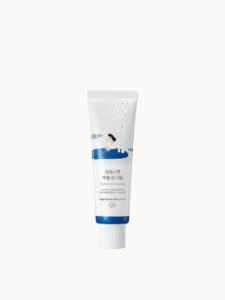 A tall conical bright white plastic tube with a bright white plastic lid that has Round Lab Birch Juice Sunscreen SPF50+ PA++++ written in bold black writing and a picture of a bright blue stripe on it, on a white background.