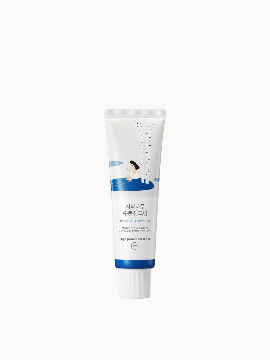 Some Of The Best Sunscreens Are Always Made In A Korean Lab | Round Lab Birch Juice Sunscreen SPF50+ PA++++ A tall conical bright white plastic tube with a bright white plastic lid that has Round Lab Birch Juice Sunscreen SPF50+ PA++++ written in bold black writing and a picture of a bright blue stripe on it, on a white background.