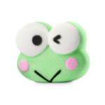 Keroppi, Tell Me. I’m Your Friend, Not Your Enemy. | Lush X Hello Kitty And Friends 2026 Range A medium light green winking cartoon frog's head shaped bath bomb that has some bright white eyes with some black pupils, some bright pink cheeks, and a thin black smile engraved on it, on a white background.