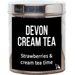Tea Tastes Terrific | Bird & Blend Tea Company Devon Cream Loose Leaf Tea A tall cylindrical bright silver metal tin with a bright silver metal lid and a black label that has Devon Cream loose Leaf Tea Strawberries and Cream Tea Time written in bright white writing and a picture of a plant with two leaves and a flower bud attached to it on it, on a white background.