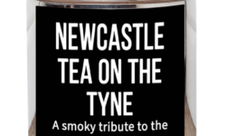 A tall cylindrical bright silver metal tin with a bright silver metal lid and a black label that has Newcastle Tea On The Tyne Loose Leaf Tea, a smoky tribute to the Angel of the North written in bright white writing and a picture of a plant with two leaves and a flower bud attached to it on it, on a white background.