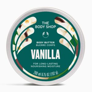 A short cylindrical Silver Metal Tin with a silver metal lid and a dark Green label that has The Body Shop Vanilla Body Butter written in bright white writing, some pictures of some small creamy white Vanilla Flowers, and some pictures of some dark Brown Vanilla Pods on it, on a white background.