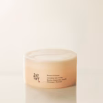 The Beauty Of Ginseng-Infused Skincare | Beauty Of Joseon Ginseng Range A short cylindrical light pink plastic tub with a matte bright white plastic lid that has Beauty Of Joseon Revive Under Eye Patch Ginseng + Retinal written in bold black writing on it, on a gradient light grey and beige background.