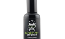 A tall cylindrical Black Glass Bottle with a matte Black Plastic lid and a black label that has Bigfoot Grooming written in bright green writing, Lemongrass Beard Oil written in bright white writing, a picture of a bearded man with some styled hair wearing a pair of green sunglasses, and a bright green stripe on it, on a white background.