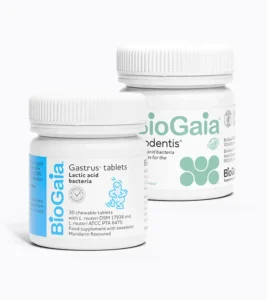 A short cylindrical bright white plastic Jar with a bright white plastic lid and a bright blue label that has BioGaia written in bright white writing, Gastrus 30 Chewable Tablets written in bold black writing, and a picture of a light blue drawn cartoon sitting baby on it next to a short cylindrical bright white plastic Jar with a bright white plastic lid and a bright white label that has BioGaia 30 ProDentist Mint lozenges written in pale green writing and a picture of several bright green dots on it, on a white background.