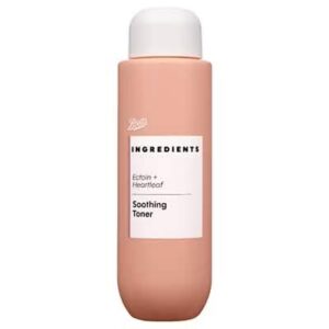 A tall cylindrical bright peach plastic bottle full of some clear liquid with a bright white plastic lid and a bright white label that has Boots Ingredients Soothing Ectoin and Heartleaf Toner written in bold black writing on it, on a white background.